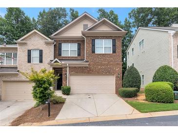 Brick front townhouse with 2-car garage and landscaped yard at 1106 Firethorne Pass, Cumming, GA 30040