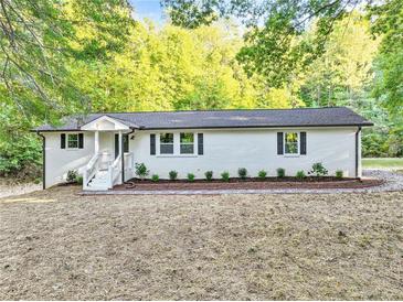 Newly renovated ranch home with white exterior, landscaping, and a large yard at 8658 Knox Bridge Hwy, Canton, GA 30114