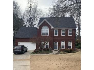 Brick two-story house with a gray roof, attached garage, and landscaping at 11060 Pinewalk Forest Cir, Alpharetta, GA 30022