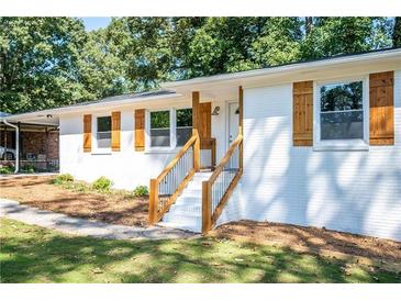 Newly renovated ranch home features white brick exterior, wood accents, and landscaped yard at 207 Okemah Se Trl, Marietta, GA 30060