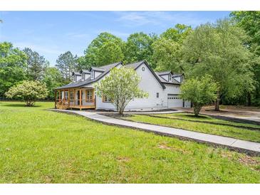 White farmhouse exterior with a wrap-around porch and landscaped yard at 4107 Old Suwanee Rd, Buford, GA 30518