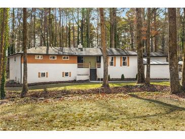 Midcentury modern home with white stucco exterior, wood accents and landscaped yard at 2019 Emerald Dr, Jonesboro, GA 30236