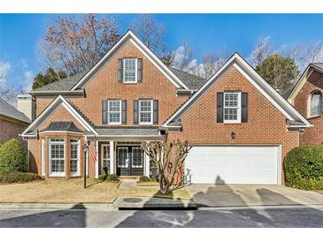 Brick two-story home with a large white garage door and manicured lawn at 1052 Brookhaven Ne Walk, Brookhaven, GA 30319