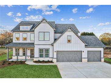 Two-story farmhouse with gray accents, three-car garage, and landscaped yard at 2799 Porches Ln, Dacula, GA 30019