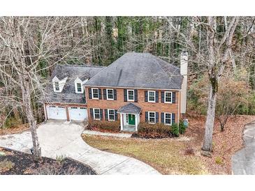 Brick house with attached two-car garage, long driveway and mature trees surrounding the property at 2269 Chimney Swift Cir, Marietta, GA 30062