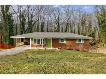 Brick ranch house with green shutters, covered porch, and landscaped lawn at 5310 Timbo Ln, Mableton, GA 30126