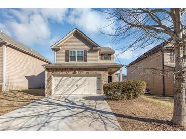 Two-story house with a beige exterior, two car garage, and manicured lawn at 6543 Woodwell Dr, Union City, GA 30291
