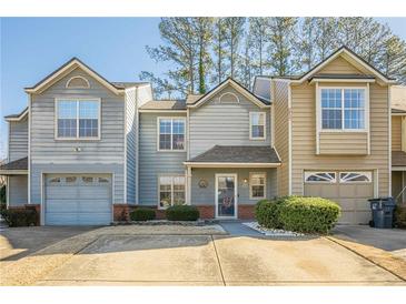 Tan and gray townhome with two-car garage and landscaped front at 3284 Long Iron Pl, Lawrenceville, GA 30044