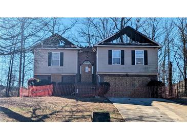 Two-story house with fire damage, boarded windows, and temporary fencing at 101 Solomon Dr, Ellenwood, GA 30294