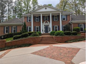 Stately brick home with white columns, dark shutters, and professionally landscaped front yard at 1120 Heards Ferry Rd, Sandy Springs, GA 30328
