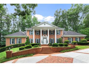 Brick home with columns, lush landscaping, and brick driveway at 1120 Heards Ferry Rd, Sandy Springs, GA 30328