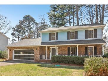 Charming two-story home with brick accents, an attached garage, and a well-manicured lawn at 201 Nouveau Sw Ct, Lilburn, GA 30047