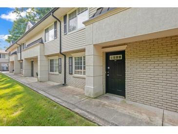 Tan brick building exterior with black doors and green lawn at 6940 Roswell Rd # 24E, Sandy Springs, GA 30328