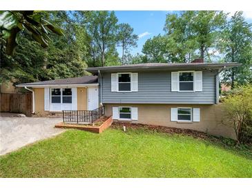 Ranch style home with gray and yellow siding, landscaped lawn, and driveway at 2666 Frontier Trl, Atlanta, GA 30341