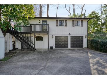 White house with dark garage doors, deck, and stairs at 2671 Caldwell Ne Rd, Brookhaven, GA 30319