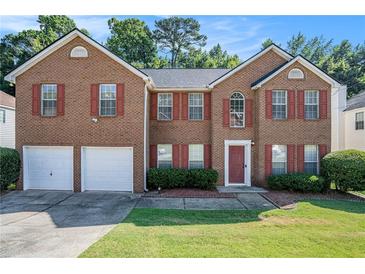 Brick two-story house with two-car garage and landscaped lawn at 1246 Carriage Trace Cir, Stone Mountain, GA 30087