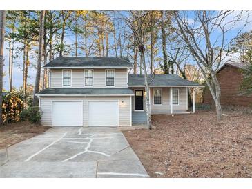 Two-story house with beige siding, attached double garage, and mature trees at 3901 W Wood Path, Stone Mountain, GA 30083