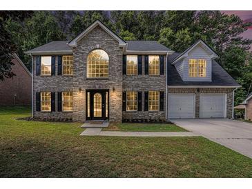 Two-story brick home with a three-car garage and landscaped lawn at 118 Bellington Dr, Mcdonough, GA 30253