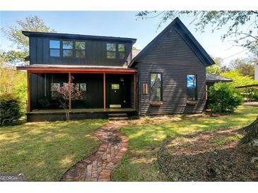 Dark-colored two-story house with a porch and brick pathway at 5152 Worsham Ne St, Covington, GA 30014