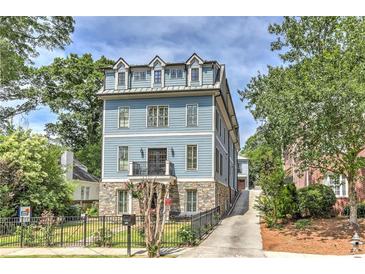 Three-story home with stone and blue siding, a driveway, and a landscaped front yard at 2972 Lookout Ne Pl, Atlanta, GA 30305