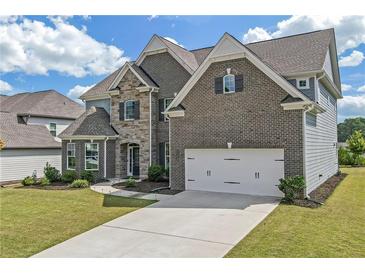 Stunning two-story brick home with a two-car garage, well-manicured lawn, and walkway to the front door at 4259 Hansford Loop, Marietta, GA 30064