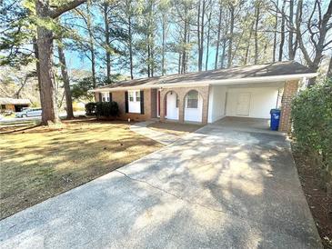 Charming brick home with a covered carport and a well-maintained front yard and a concrete driveway at 869 Meadow Rock Way, Stone Mountain, GA 30083