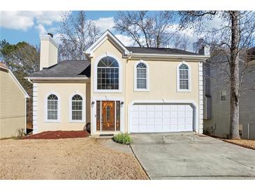 Two-story house with stucco exterior, attached garage, and landscaping at 707 Stonemill Mnr, Lithonia, GA 30058