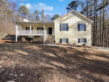 House exterior featuring a yellow vinyl siding, covered porch, and a landscaped yard at 114 Blake Cv, Douglasville, GA 30134