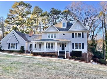 Two-story house with a wraparound porch and mature trees in the yard at 4817 Carlene Sw Way, Lilburn, GA 30047