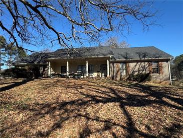 Brick ranch house with covered porch and mature trees at 144 Rockbridge Sw Rd, Lilburn, GA 30047