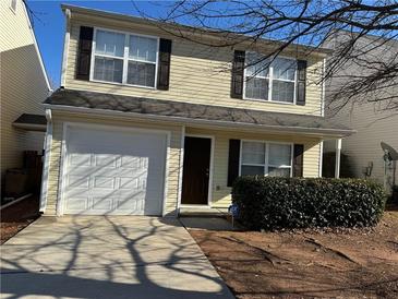 Tan two-story house with a white garage door and dark brown shutters at 444 Kara Ln, Mcdonough, GA 30253