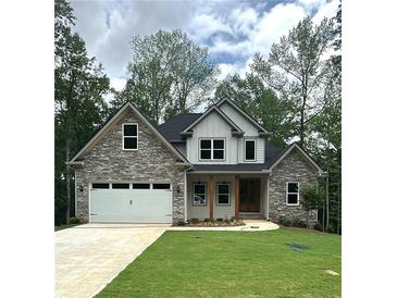Charming two-story home featuring stone accents, a well-manicured lawn, and an attached two-car garage at 321 Evie Ln, Canton, GA 30115