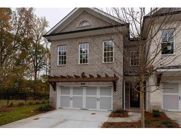 Brick front exterior of a two-story townhome with a two-car garage and pergola at 131 Wards Crossing Way # 19, Johns Creek, GA 30022