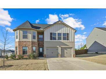 Two-story house with brick and siding, two-car garage, and a well-manicured lawn at 12 Enclave Blvd, Covington, GA 30014