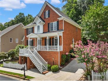 Charming two-story red brick home featuring a welcoming front porch and beautifully landscaped yard at 2750 Olde Towne Pkwy, Duluth, GA 30097