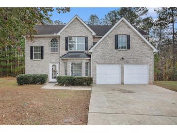 Two-story brick home with a two-car garage and landscaped lawn at 6876 Wildboar Dr, Fairburn, GA 30213
