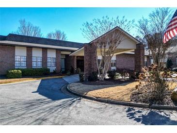 Brick building with a covered entrance, landscaping, and American flag at 475 Mount Vernon Ne Hwy # C-220, Sandy Springs, GA 30328