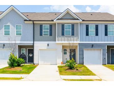 Two story townhouses with gray siding, white garage doors, and landscaping at 7144 Gladstone Cir, Stonecrest, GA 30038