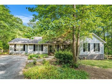 Charming single-story home with inviting front yard, black shutters, and lush landscaping at 675 Mayes Rd, Powder Springs, GA 30127