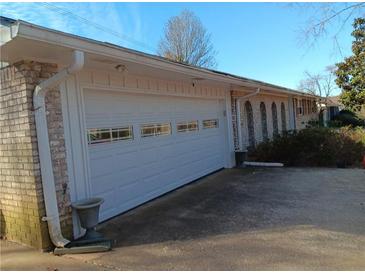 White garage door with windows, brick exterior, and long driveway at 2479 Kingsland Dr, Dunwoody, GA 30360