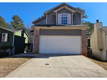 Two-story house with gray siding, brick accents, and a white garage door at 1334 To Lani Farm Rd, Stone Mountain, GA 30083