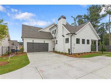 Stunning white farmhouse exterior with gray roof, two-car garage, and manicured lawn at 515 Pearl St, Cumming, GA 30040