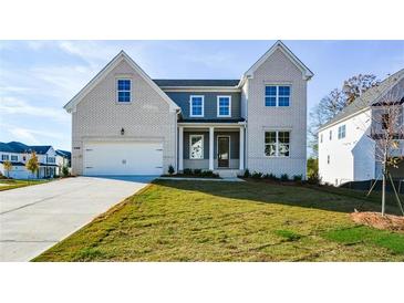 Two-story house with white brick and gray siding, featuring a front porch and attached two-car garage at 5435 Crestline View Rd, Cumming, GA 30028
