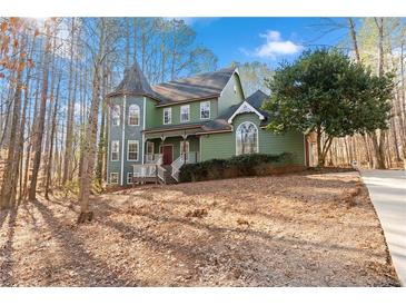 Green two-story house with a turret, situated on a wooded lot at 7825 Brands Hatch Blvd, Cumming, GA 30040