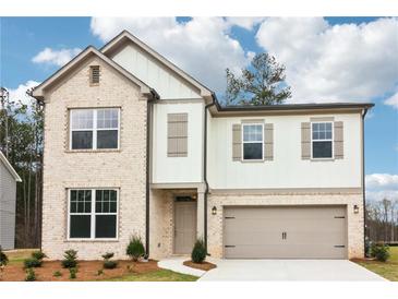 Charming two-story home with a brick and siding exterior, complemented by a well-manicured lawn and two-car garage at 7289 Eton Ln, Locust Grove, GA 30248