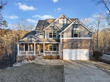Inviting two-story home with stone accents, a well-manicured lawn, and attached two car garage at 9475 Dunmoore Dr, Cumming, GA 30028