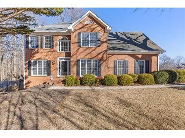 Brick two-story house with a landscaped lawn and mature trees at 5480 Landseer Way, Cumming, GA 30040