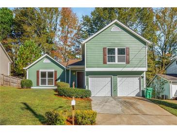 Charming green house with two-car garage and well-manicured lawn at 5541 Downs Way, Lithonia, GA 30058