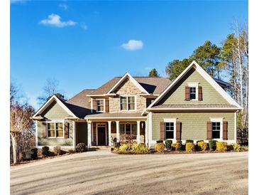 Two story house with green siding, stone accents, and a front porch at 121 Harmony Oaks Trl, Canton, GA 30115