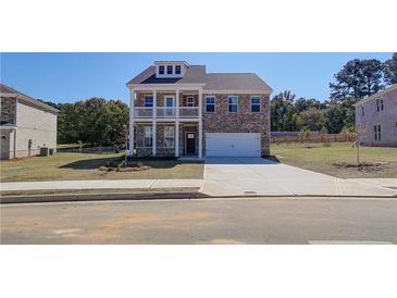 Two-story brick home with balcony, attached garage, and landscaped yard at 205 Chiswick Loop, Stockbridge, GA 30281